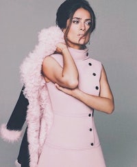 a woman in a pink dress posing with a fur coat