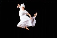 a woman in a white dress is jumping in the air