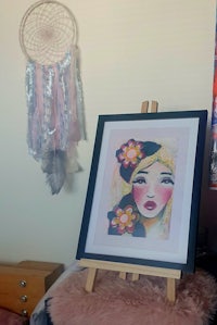 a framed painting of a girl in a room with a dream catcher