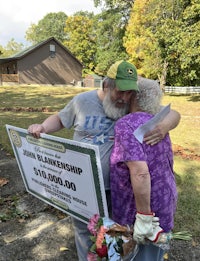 a man and woman hugging in front of a large check