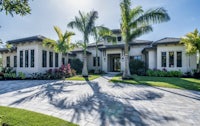 a beautiful home with palm trees and a driveway