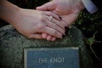 a couple holding hands next to a stone with the knot written on it
