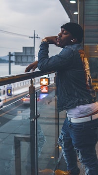 a man leaning on a railing with a view of the city