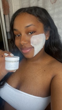 a woman holding a jar of face mask