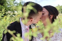 a bride and groom kissing in a field of flowers