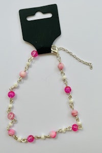 a pink and white bracelet with a tag on it