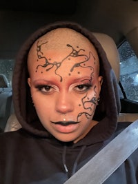 a woman with a tattoo on her head is sitting in a car