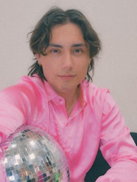 a man in a pink shirt holding a disco ball