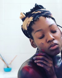 a black woman in a bathroom with paint on her face
