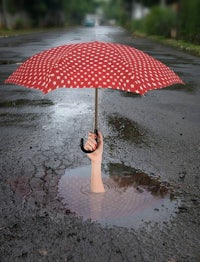 a hand holding an umbrella in a puddle