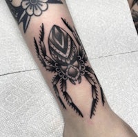 a black and white spider tattoo on the forearm