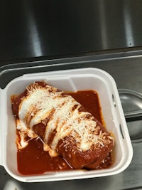 a white container with a stuffed enchilada sitting on top of it
