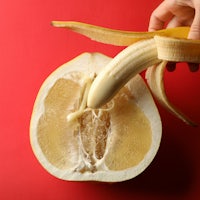 a person peeling a banana on a red background