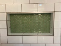 a green tiled wall in a bathroom