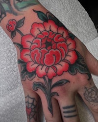 a hand with a red flower tattoo on it