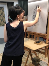 a woman drawing a figure on an easel