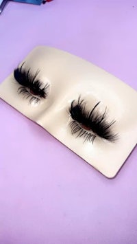a pair of fake eyelashes on a purple surface
