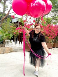 a woman holding a bunch of pink balloons