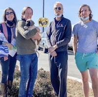 a group of people standing in a parking lot with a dog