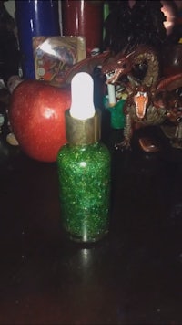 a bottle of green glitter oil on a table