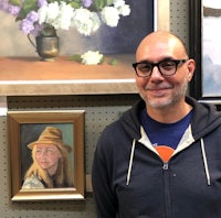 a man standing in front of a painting of a woman