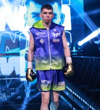 a boxer in a blue and green uniform walking on a runway