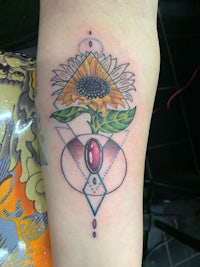 a tattoo with a sunflower and a stone