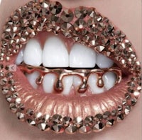 a woman's mouth is covered in gold and diamonds
