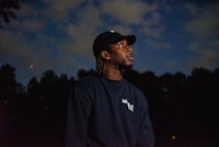 a man in a hat standing in a field at night