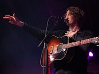 a man holding an acoustic guitar and singing into a microphone