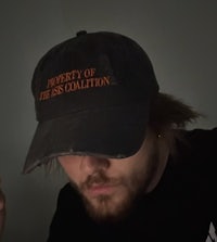 a man wearing a hat that says property of the sea colony