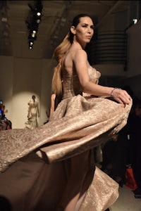 a woman in a gown walking down the runway