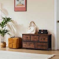 a room with a wooden chest of drawers and a potted plant