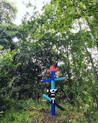 a colorful cross in the middle of a wooded area