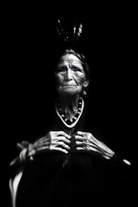 a black and white photo of an old woman holding a skeleton