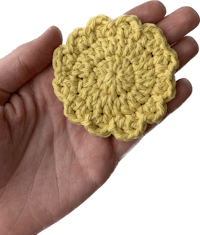 a person holding a yellow crocheted flower