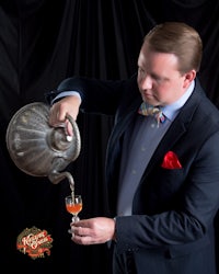 a man in a suit pouring a drink into a pot
