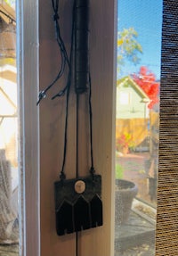 a black candle holder hanging on a window sill