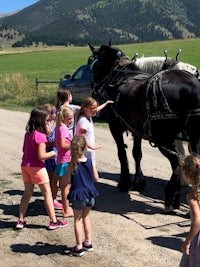 a group of children standing next to a horse drawn carriage