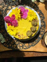 a yellow cake on a table with flowers on it