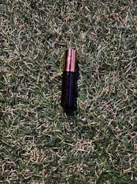 a bottle of lipstick laying on the grass
