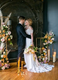 a bride and groom standing in front of a fireplace with candles