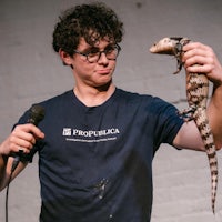 a man holding a lizard while holding a microphone