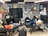 a group of people sitting in a tattoo shop