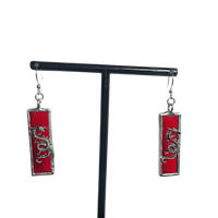 a pair of red and silver earrings on a stand