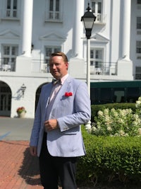 a man in a blue suit standing in front of a white building