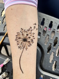 a person with a dandelion tattoo on their arm