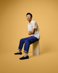 a man sitting on top of a box on a yellow background