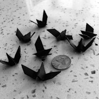 black origami cranes on a table next to a quarter