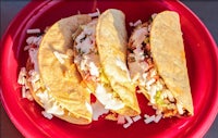 three tacos are sitting on a red plate